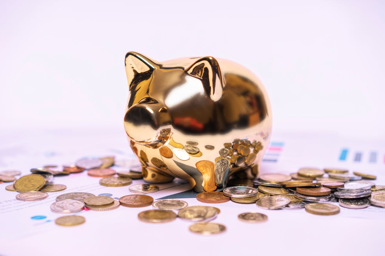 services-img Shiny golden piggy bank on financial documents with scattered coins symbolizes savings.