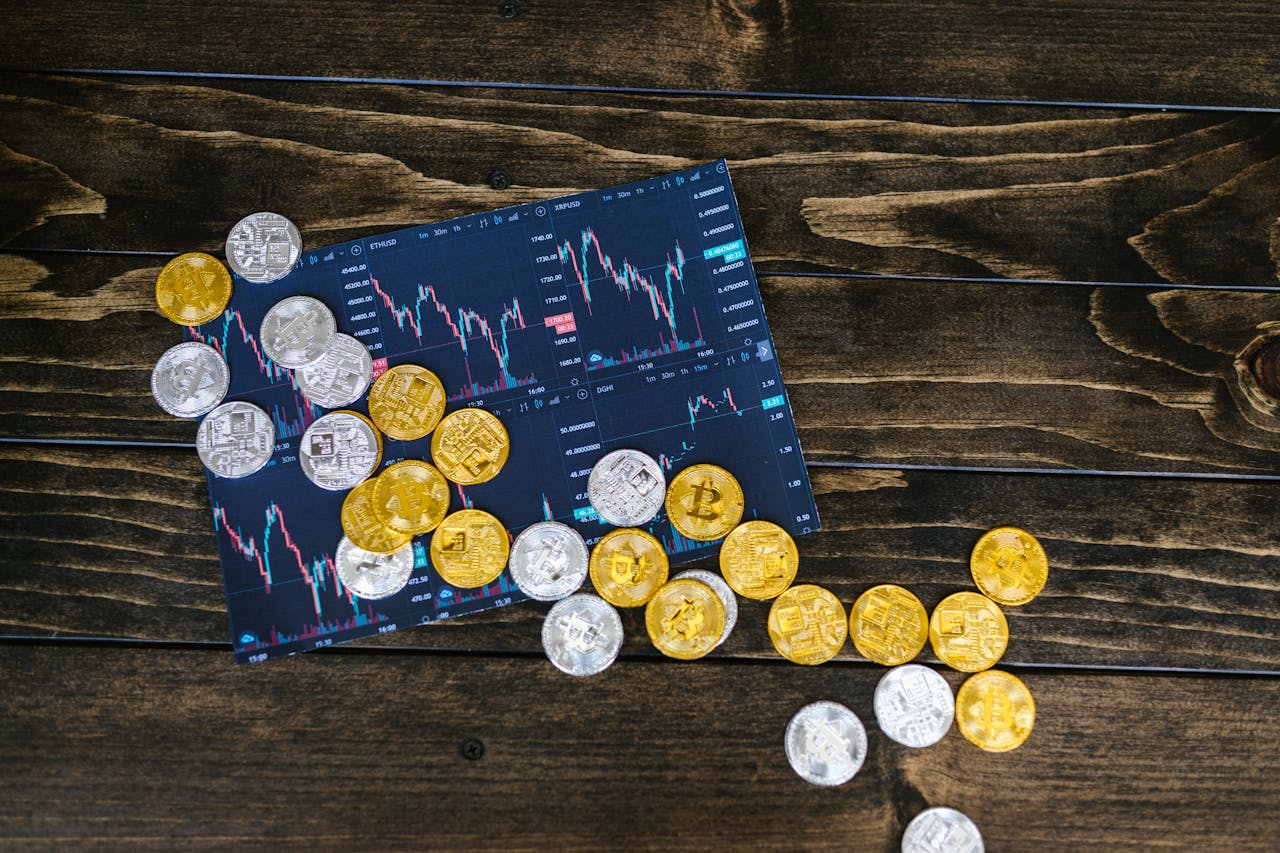 services-01 Gold and silver cryptocurrency coins scattered on a trading chart over a wooden table.